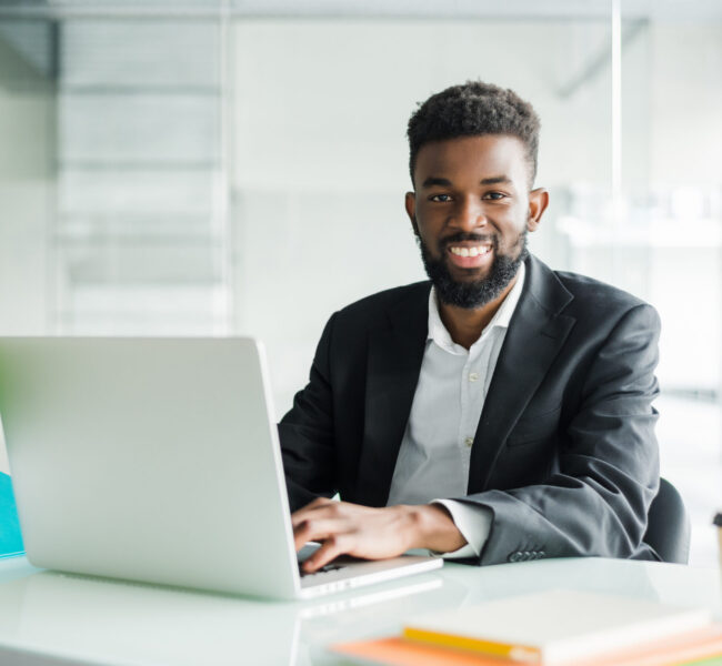 portrait of handsome African black young business man working on laptop computer at office desk